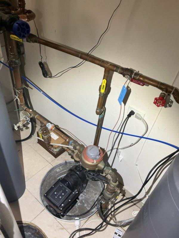 Responded to service call for loud noise coming from booster pump system in utility room. Upon arrival, inspected the complete water pressure booster system including the pressure tank, circulator pump, control unit, and associated copper piping. Identified excessive noise originating from the pump motor and vibration throughout the system. Evaluated the pump mounting, electrical connections, and pressure settings on the digital control panel. Checked pressure vessel for proper air charge and inspected all valves and connections for secure operation. Documented existing system configuration with copper supply lines, brass fittings, and flexible blue tubing connections. Assessed the overall condition of the 17-year-old installation including signs of mineral deposits and age-related wear on components. Provided recommendations for addressing the noise issue and ensuring continued reliable operation of the booster pump system.