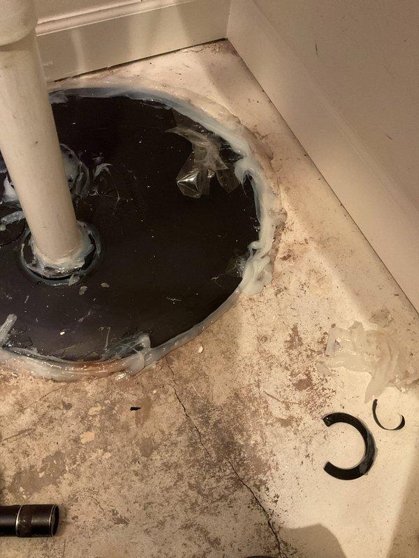 Responded to warranty callback for ejector pit installation completed six weeks prior. Upon inspection, confirmed customer complaint of sewer gas odor and drain fly infestation originating from improperly sealed ejector pit gaskets. Found rubber grommets around PVC discharge pipes compromised and deteriorated, allowing sewer gas escape into living space. Standing water observed in ejector pit with visible debris accumulation. Bathroom floor showed evidence of water overflow and unsanitary conditions with dark water pooling around toilet base. Removed failed rubber seals and cleaned pit opening perimeter. Installed new properly-sized rubber grommets around both discharge pipes, ensuring watertight seal to prevent gas infiltration. Verified all penetrations sealed and no gaps present around piping. Tested ejector pump operation and confirmed proper cycling. Cleaned surrounding area and removed standing water. Advised customer that drain fly issue should resolve within days as breeding so