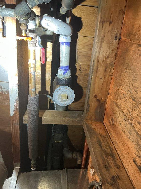 Responded to service call for residential property with water service currently shut off. Conducted thorough assessment of existing plumbing infrastructure, which consisted of aging galvanized piping requiring replacement. Inspected copper pipe assembly installed through wooden structural framing in crawlspace area, noting varying degrees of patina and oxidation indicating different installation periods. Examined existing water supply system including white PVC piping, insulated copper lines, flow meter installation, and associated valves and fittings. Documented condition of pipe insulation, metal flanges, and connection points throughout the accessible plumbing system. Photographed all relevant components to support comprehensive estimate for complete piping replacement project. Provided detailed assessment and recommendations for upgrading from deteriorated galvanized system to modern piping materials.