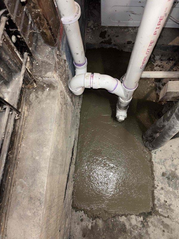 Conducted residential drain and sewer estimate in basement area with significant standing water accumulation in floor depression. Documented existing Charlotte Pipe PVC drainage system configuration and identified moisture infiltration issues affecting concrete surfaces and wooden structural elements. Coordination required for follow-up visit to excavate and address drainage concerns, with additional consultation scheduled to review remediation options and system modifications with property owner.