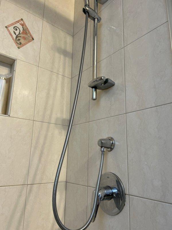 Serviced and inspected Grohe shower valve assembly and handheld shower system in residential bathroom. Addressed water spots and mineral deposits on chrome fixtures, ensuring proper operation of single-lever control valve and sliding rail mechanism. Verified functionality of diverter valve and confirmed all components were properly mounted and operating within manufacturer specifications.