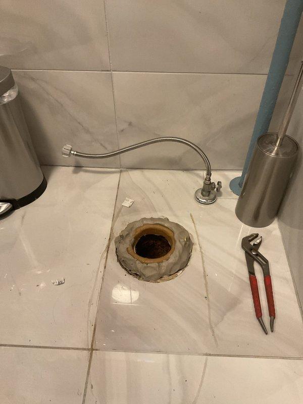 Responded to callback for persistent toilet seal leak in 106-year-old home following recent repair attempt. Upon inspection, discovered compromised wax ring seal and deteriorated closet flange contributing to ongoing water seepage. Removed toilet to access flange assembly, which showed significant corrosion and rust staining on surrounding floor drain components consistent with chronic moisture exposure. Replaced failed wax ring with new seal, inspected and reinforced closet flange mounting, and reinstalled toilet with proper torque specifications on closet bolts. Tested flush cycles and verified complete elimination of leak at base. Addressed underlying issues from previous repair to ensure permanent resolution.
