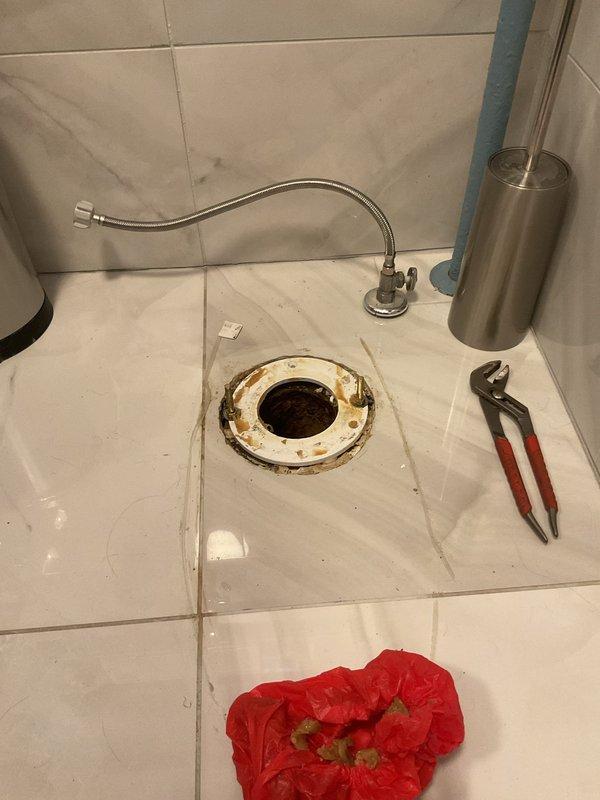 Responded to callback for persistent toilet seal leak in 106-year-old home following recent repair attempt. Upon inspection, discovered compromised wax ring seal and deteriorated closet flange contributing to ongoing water seepage. Removed toilet to access flange assembly, which showed significant corrosion and rust staining on surrounding floor drain components consistent with chronic moisture exposure. Replaced failed wax ring with new seal, inspected and reinforced closet flange mounting, and reinstalled toilet with proper torque specifications on closet bolts. Tested flush cycles and verified complete elimination of leak at base. Addressed underlying issues from previous repair to ensure permanent resolution.