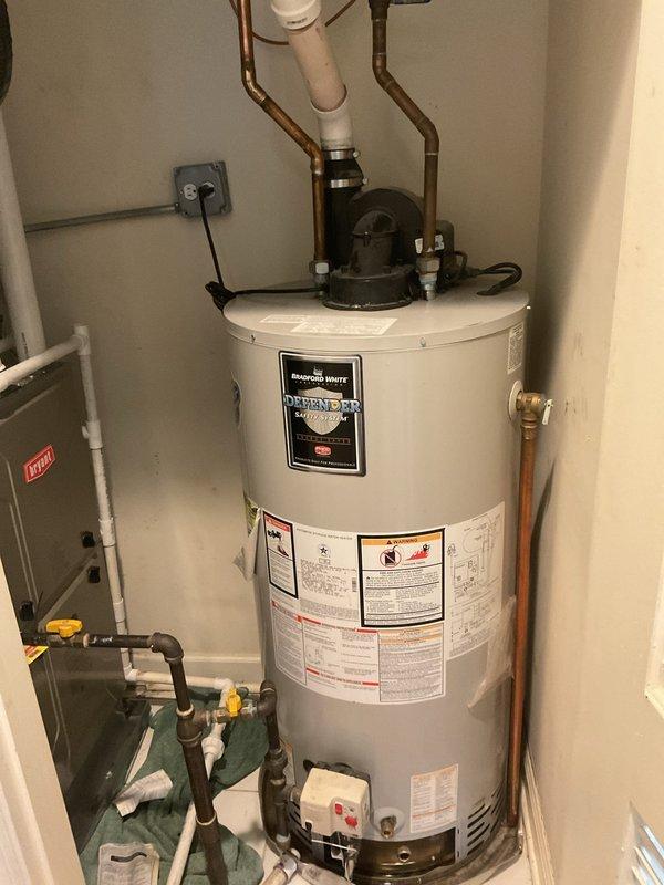 Responded to water leak complaint affecting unit below with no hot water available. Upon inspection, located Bradford White Defender water heater in utility closet and performed visual assessment of all plumbing connections, including copper supply lines, PVC venting, and lower gas piping with yellow-handled valves. Documented water heater installation with detailed photographs showing unit specifications, safety labels, and all visible pipe connections to determine source of reported leak and loss of hot water service.