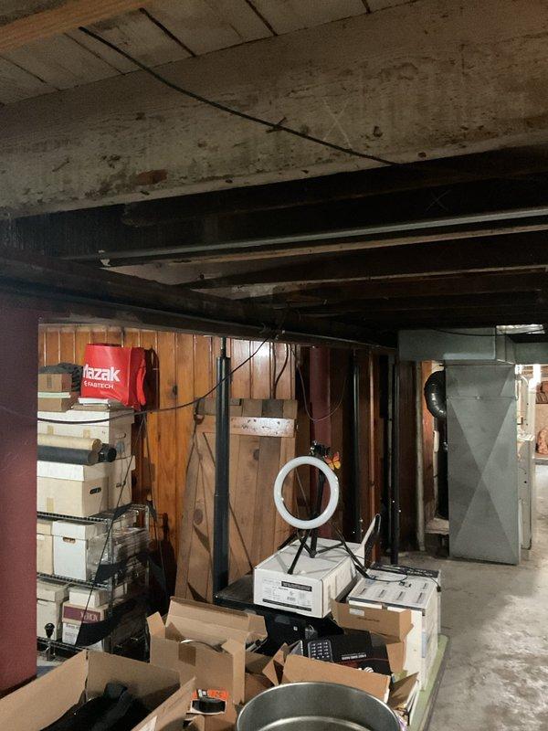 Completed plumbing piping installation in unfinished basement utility area. Installed new piping infrastructure throughout the space, working around existing structural elements including exposed ceiling joists, support posts, and concrete beams. Routed piping to accommodate stored equipment and maintain clearances for future access to utility systems.