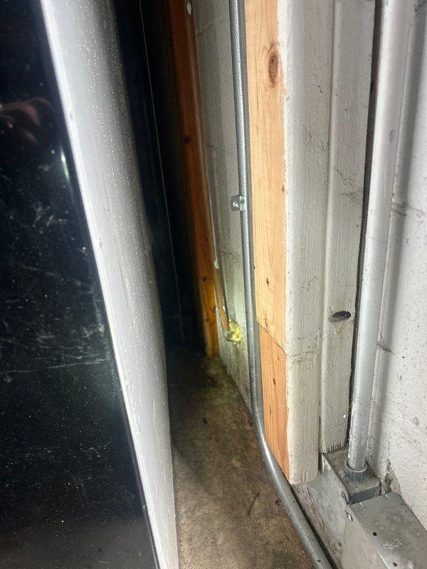 Responded to water leak affecting outdoor line beneath deck and garage area. Upon inspection, located compromised water supply line running through basement utility area with visible moisture damage on concrete wall surfaces and aging copper piping system. Assessed refrigerator water supply connection for modification as requested. Documented existing plumbing infrastructure including oxidized copper lines, shut-off valves, and routing configuration through exposed ceiling joists and along foundation walls.