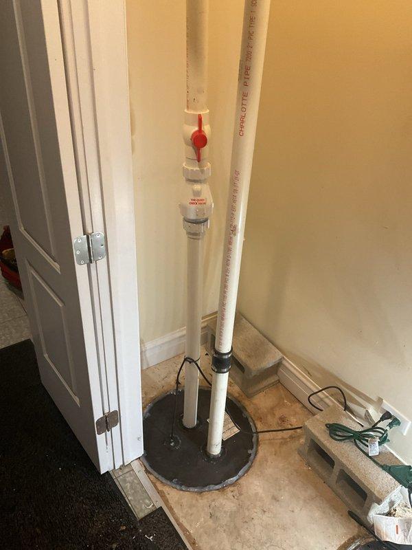 Installed new sump pump system in basement utility area, including vertical PVC discharge pipe with ball valve, wall-mounted digital control unit with backup battery system, and proper floor basin assembly. Secured all components with appropriate mounting brackets and established electrical connections to ensure reliable operation and basement flood protection.