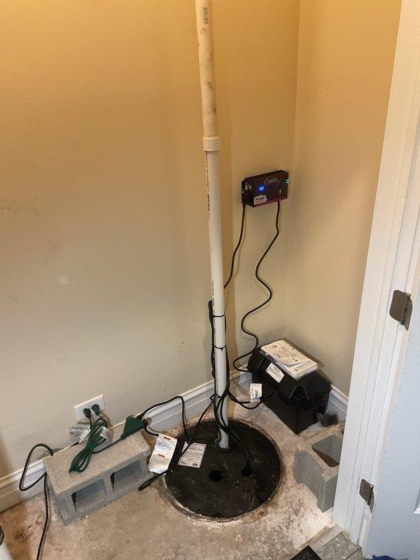 Installed new sump pump system in basement utility area, including vertical PVC discharge pipe with ball valve, wall-mounted digital control unit with backup battery system, and proper floor basin assembly. Secured all components with appropriate mounting brackets and established electrical connections to ensure reliable operation and basement flood protection.