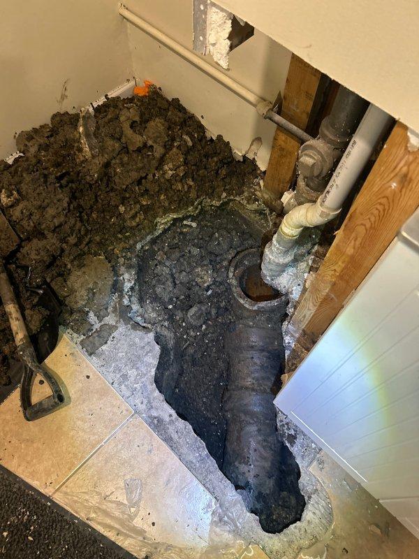 Responded to severe foundation and plumbing infrastructure damage in residential basement area. Assessed extensive water intrusion that caused structural floor failure, exposed saturated soil accumulation, and deteriorated plumbing systems including corroded metal pipes and stained PVC drainage lines. Documented compromised concrete foundation with significant cracking, mineral deposits on vertical pipe penetrations, and water-damaged wooden framing members requiring comprehensive repair and restoration work.