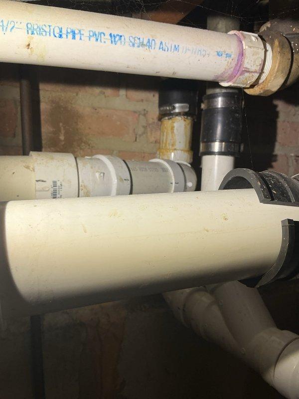 Performed smoke test on plumbing vent system originating from sump pump area to diagnose source of intermittent sewage odor. Inspected PVC drainage and venting infrastructure in basement, examining pipe connections, couplings, and seals for potential breaks or gaps that could allow sewer gas infiltration. Documented condition of plumbing system including multiple pipe joints, rubber couplings, and vent stack configuration for further evaluation and repair recommendations.