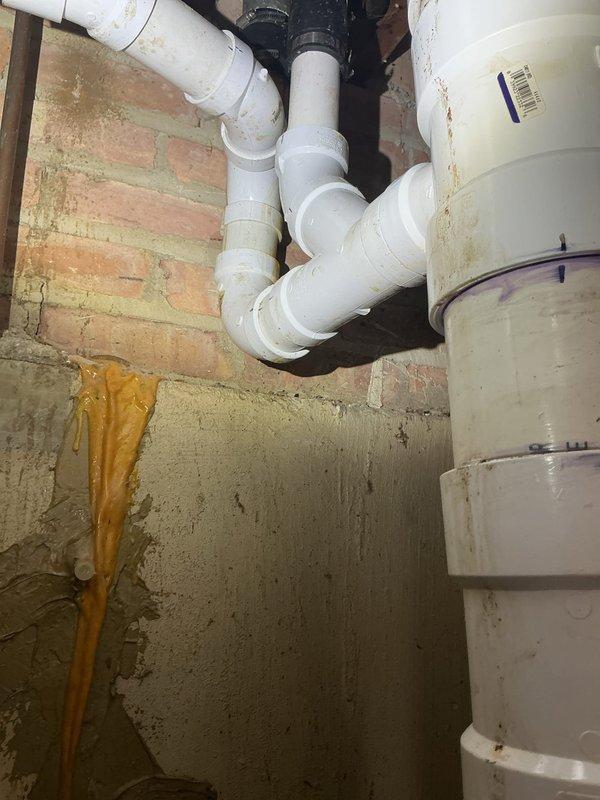 Performed smoke test on plumbing vent system originating from sump pump area to diagnose source of intermittent sewage odor. Inspected PVC drainage and venting infrastructure in basement, examining pipe connections, couplings, and seals for potential breaks or gaps that could allow sewer gas infiltration. Documented condition of plumbing system including multiple pipe joints, rubber couplings, and vent stack configuration for further evaluation and repair recommendations.