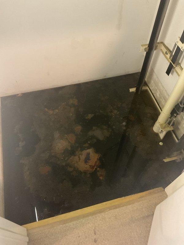 Responded to a clogged drain complaint in a basement utility area where a floor trap was backing up and causing water damage. Upon inspection, found extensive moisture damage and deterioration to the concrete floor surrounding the floor drain, with significant staining and discoloration indicating recurring drainage issues. Cleared the blocked floor trap to restore proper drainage function and prevent further water accumulation in the affected area.