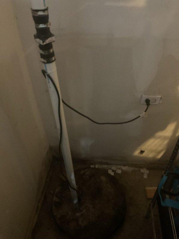 Responded to emergency call for basement flooding following recent rain storm. Upon arrival, inspected sump pump system and surrounding area, discovering failed sump pump operation that resulted in water intrusion and subsequent damage to foundation drainage tiles. 

Documented extensive water damage in utility room area, including standing water, debris accumulation, and floor contamination around water heater and sump pump location. Identified moisture infiltration through foundation wall system with visible water staining and dark discoloration on interior wall surfaces.

Performed exploratory investigation by opening section of interior drywall to assess extent of water damage behind wall cavity. Inspection revealed compromised wall structure with significant water staining and possible microbial growth on back wall surfaces. Located horizontal PVC drainage pipe running through wall cavity. Confirmed presence of dimpled drainage membrane at floor level, indicating previous waterpro