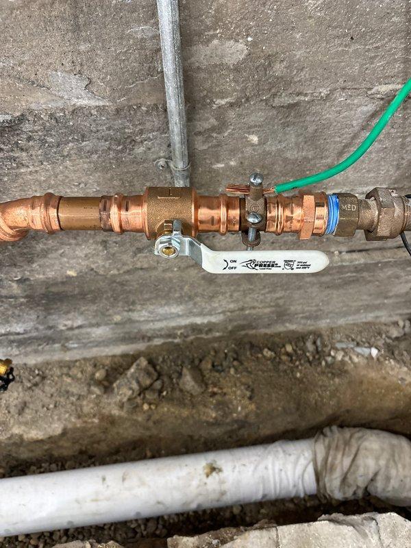 Replaced heavily corroded copper water supply piping that exhibited significant rust deterioration and mineral buildup. Installed new copper pipe assembly with ball valve shutoff, compression fittings, and proper connections to existing plumbing system mounted on concrete block wall. All associated fittings included with lifetime workmanship warranty provided.