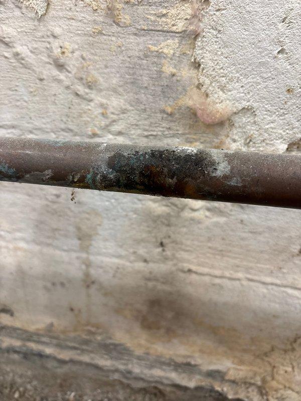 Replaced heavily corroded copper water supply piping that exhibited significant rust deterioration and mineral buildup. Installed new copper pipe assembly with ball valve shutoff, compression fittings, and proper connections to existing plumbing system mounted on concrete block wall. All associated fittings included with lifetime workmanship warranty provided.