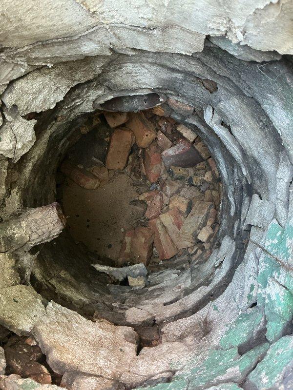 Conducted a comprehensive drain and sewer estimate for a residential catch basin requiring repair. Upon inspection, confirmed the presence of significant structural deterioration with multiple layers of compromised liner material peeling and separating from the basin walls, along with an accumulation of brick debris and masonry fragments at the bottom of the structure as initially identified during the home inspection. Documented the extensive damage through photographic evidence showing the circular opening with degraded concentric layers, mineral deposits, sediment buildup, and various broken brick pieces obstructing proper drainage function.
