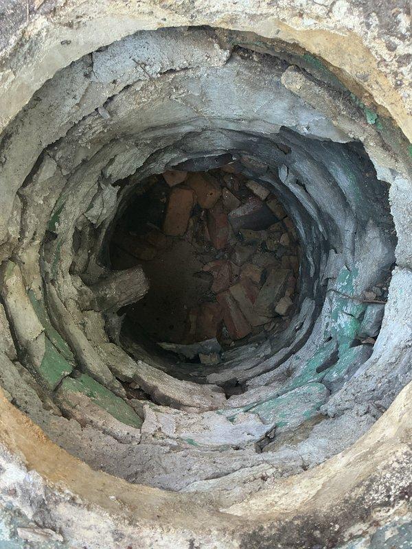 Conducted a comprehensive drain and sewer estimate for a residential catch basin requiring repair. Upon inspection, confirmed the presence of significant structural deterioration with multiple layers of compromised liner material peeling and separating from the basin walls, along with an accumulation of brick debris and masonry fragments at the bottom of the structure as initially identified during the home inspection. Documented the extensive damage through photographic evidence showing the circular opening with degraded concentric layers, mineral deposits, sediment buildup, and various broken brick pieces obstructing proper drainage function.