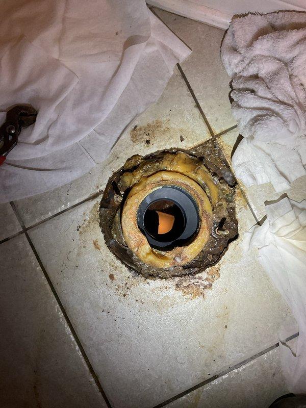 Responded to a plugged toilet in the basement of a 20-year-old home. Upon arrival, removed the toilet to access the flange and investigate the blockage. Cleared the obstruction and inspected the toilet flange, which showed signs of age, water staining, and deterioration around the seal area. Reinstalled the toilet with protective materials placed around the work area to maintain cleanliness. Tested the toilet for proper flush operation and verified drainage was restored to normal function.