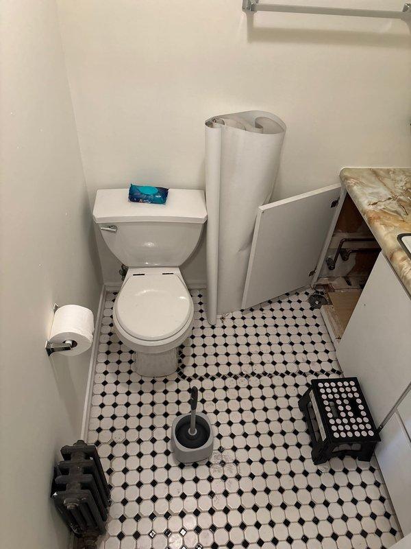 Responded to reported water leak originating from second-floor bathroom and laundry room affecting first-floor unit in century-old home. Investigated paint bubbling on three walls with no active water present at time of inspection. Conducted visual assessment of upper-unit bathroom, documenting conditions of plumbing fixtures, vanity cabinet, shower enclosure, and accessible pipe connections beneath sink. Photographed bathroom layout including floor tile pattern, toilet, vanity with marble countertop, and glass shower door to establish baseline conditions for ongoing moisture monitoring and potential follow-up with upper-unit plumbing system.