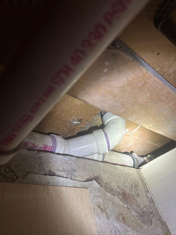 Completed plumbing estimate for bathroom piping installation. Assessed existing white PVC drainage and waste water lines beneath floor structure, including elbow joints and connections within wooden framed cavity. Evaluated bathroom plumbing configuration including toilet installation, under-vanity plumbing connections, and overall drainage system layout to provide accurate piping estimate.