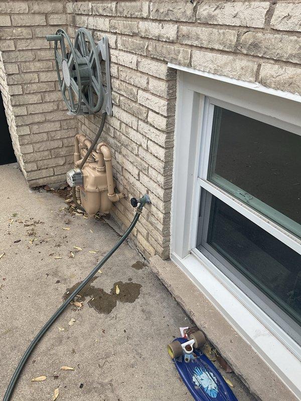 Responded to service call for exterior drainage system backing up into residence during rain events. Performed camera inspection of previously installed outdoor drain line to assess functionality and identify potential blockages or structural issues. Documented existing plumbing configuration including exposed gas and water supply lines at exterior wall connection point and interior utility area piping layout for comprehensive evaluation of drainage system performance.