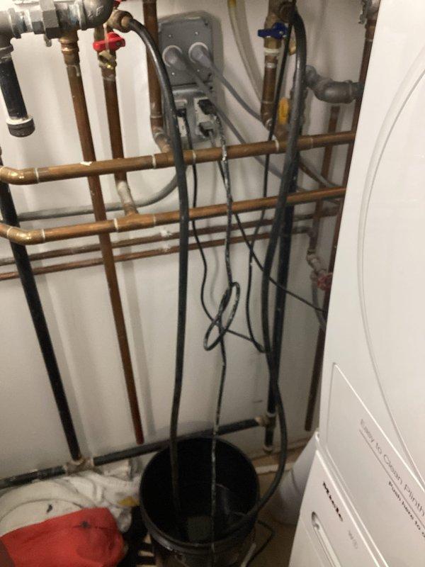 Completed comprehensive VIP plumbing maintenance inspection of residential mechanical room and associated systems. Inspected heating system components including copper piping, manifold control panel with gauges, and valve assemblies with proper operation confirmed. Removed and cleaned severely clogged drain strainer showing significant rust-colored residue, hair, and debris accumulation; reinstalled after thorough cleaning to restore proper drainage function.