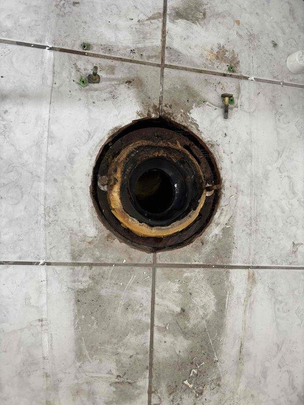 Responded to water leak affecting second floor originating from third floor bathroom area in 135-year-old residence. Conducted thorough inspection of potential source points including wall cavity between bathroom and kitchen, toilet connections, and sink plumbing. Investigated aged floor drain fixture showing significant corrosion and deterioration, examined ceiling-mounted ventilation system, and assessed surrounding tile work displaying water damage indicators. Documented conditions with photographic evidence for record. Four-hour diagnostic service completed to identify leak source in historic plumbing system.