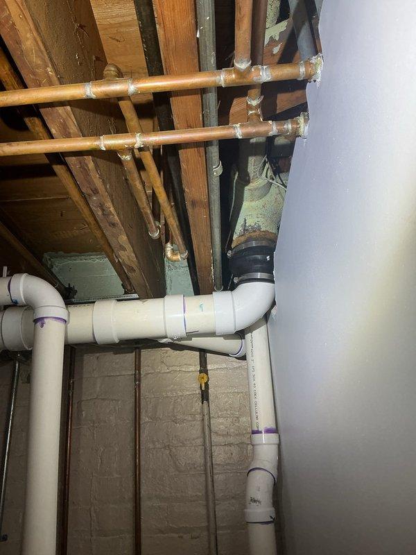 Conducted diagnostic evaluation for persistent sewer odor in basement occurring during washing machine operation. Inspected basement plumbing infrastructure including drainage system, floor drains, and venting configuration. Documented existing copper supply lines, PVC drainage piping with proper purple primer application, and basement bathroom facilities to assess potential sources of sewer gas infiltration. Provided estimate for smoke testing services to identify defective drain traps, missing vent caps, or compromised pipe connections causing odor issues despite previous camera inspection and floor drain testing.
