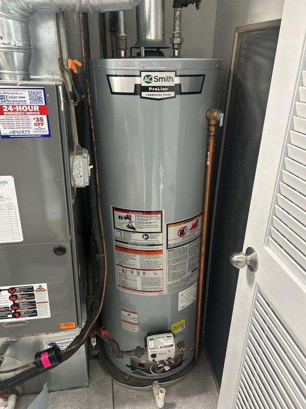 # Tanked Water Heater Igniter Repair

Responded to a priority service call for an A.O. Smith ProLine residential gas water heater experiencing igniter failure in a 1970s home. The unit was installed in a floor-level mechanical closet alongside HVAC equipment in a confined space typical of older residential construction.

Upon arrival, performed diagnostic assessment of the water heater's ignition system. Confirmed the igniter assembly had failed, preventing the burner from lighting and resulting in no hot water production. The issue had been ongoing for approximately one day prior to service.

Removed the failed igniter assembly, which included the motor/pump component, electrical wiring harnesses, and associated sensor components. Documented the removed parts, which showed typical wear consistent with the age of the installation. The igniter assembly featured multiple wire connections in various colors (white, orange, black, and red), along with a white plastic valve/sensor component 