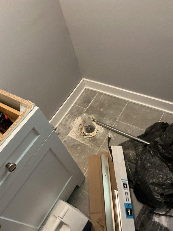Completed toilet removal and prepared bathroom for renovation work coordinated with restoration company. Bathroom floor was cleared of existing toilet fixture, exposing the toilet flange for future reinstallation. Work area was staged with construction materials and debris removal in progress, with flooring left clean and accessible for ongoing restoration activities.