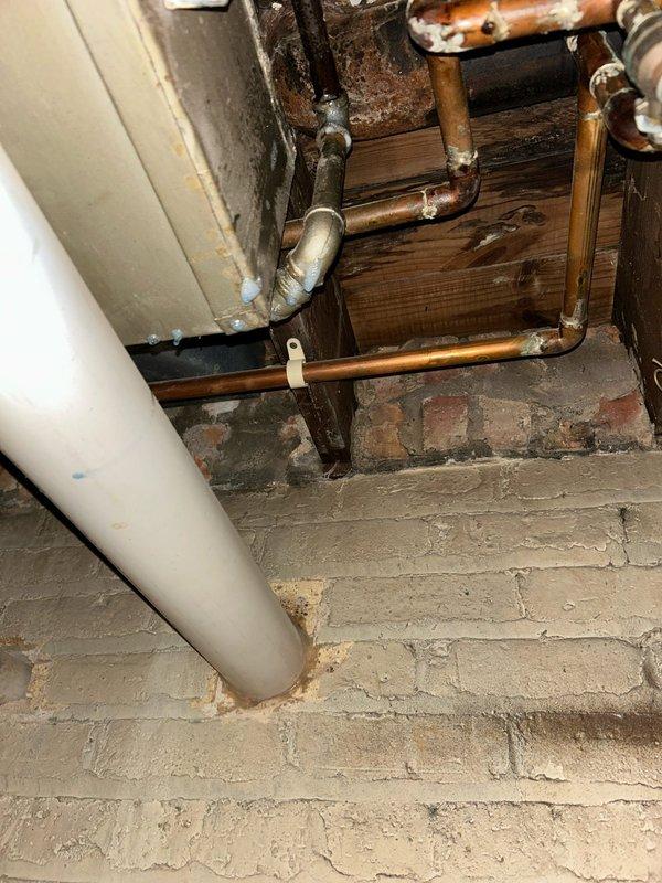Responded to reported gas odor in basement near furnace in 80-year-old residence. Conducted comprehensive visual inspection of natural gas meter, black iron gas piping, shut-off valves, and all associated connections throughout the basement mechanical room. Performed systematic pressure test on gas distribution system to identify source of leak. Inspected all threaded connections, elbow fittings, and unions on black steel gas lines extending from meter. Examined condition of aging copper water supply lines and verified no cross-contamination issues. Documented existing infrastructure including deteriorated wooden framing, corroded copper piping with verdigris formation, and overall condition of utility space. Verified proper operation of gas meter and shut-off valve accessibility. Completed leak detection protocol using approved testing methods on all gas piping joints and connections visible in mechanical room area.