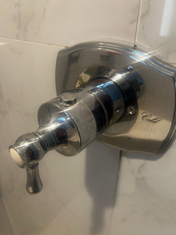 Responded to shower valve malfunction and completed fixture repair. Removed and inspected flow restrictor showing significant mineral buildup and deposits. Serviced Grohe shower control valve assembly and restored proper water flow operation.