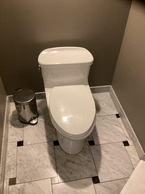 Responded to service call for rattling noise in plumbing pipes throughout the residence. Conducted thorough inspection of accessible plumbing system including bathroom fixtures and basement piping installation. Examined toilet installation, water supply lines, and drainage system in bathroom area with marble tile flooring. Inspected basement plumbing configuration including white PVC drainage pipes with quiet check valve assembly, copper water supply lines with mounting brackets, and pipe penetrations through concrete floor. Documented existing plumbing installation with photographic evidence for assessment purposes. Identified potential water hammer or loose pipe mounting as probable cause of rattling sounds reported by homeowner.
