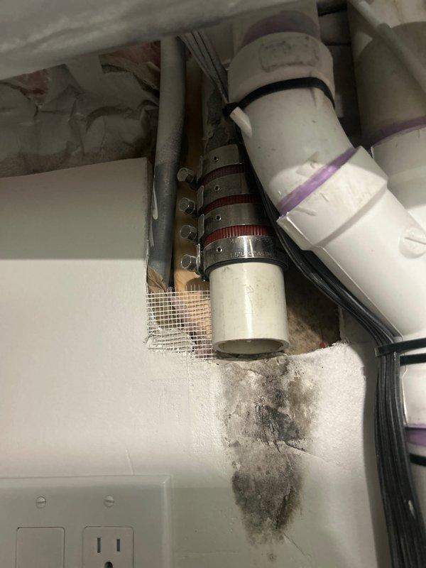 Responded to service call for two toilets experiencing intermittent running issues in 110-year-old residential property. Inspected TOTO brand toilet with tank lid removed, identifying significant rust and mineral deposits in tank water and around flush valve components. Found deteriorated flapper seal with reddish-brown discoloration and mineral buildup affecting proper sealing function. Blue float valve assembly and fill valve mechanism showed signs of age-related wear. Documented corroded mounting hardware and internal component degradation contributing to running toilet condition.

During comprehensive plumbing inspection, identified water damage and dark staining below exposed PVC pipe connection in utility area, indicating historical moisture intrusion. Observed multiple metal hose clamps securing pipe joint with visible purple primer markings. Staining pattern suggests ongoing or past leakage at connection point requiring attention. Documented conditions with photographic evidenc