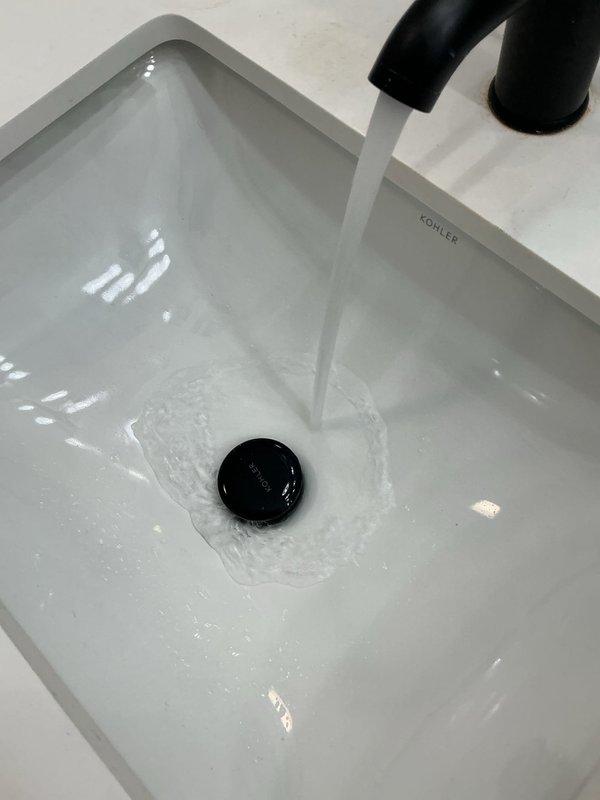 Completed installation of Kohler rectangular basin sink with matte black faucet fixture and garbage disposal unit. Configured PVC P-trap drainage system with proper venting, verified water flow and drainage functionality, and confirmed all connections are secure and leak-free under the cabinet assembly.