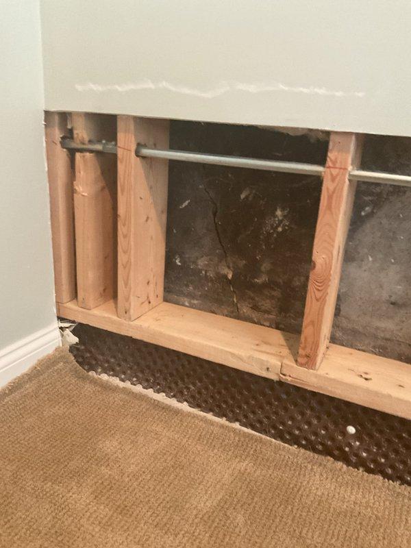 Completed sump pump installation in basement area with pre-ordered parts. Removed section of drywall to access wall cavity, exposing wooden studs and existing plumbing infrastructure. Installed dimpled drainage membrane and waterproofing barrier at base of wall cavity to direct water flow toward sump pump location. Documented equipment specifications and installation progress with detailed photography for service records.