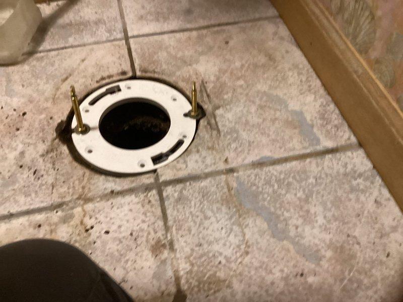 Responded to customer request for toilet flange repair at afternoon appointment. Removed existing deteriorated toilet flange that showed significant buildup of debris, grime, and sediment accumulation around the drain opening. Installed new white PVC closet flange with brass mounting brackets, securing it flush to the tiled bathroom floor. Ensured proper alignment and stable mounting preparation for future toilet reinstallation.