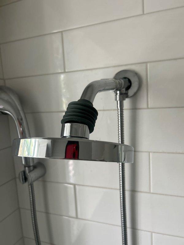 Responded to service call for leaking shower diverter. Upon inspection, identified that the diverter valve was failing to properly seal when activated to the overhead position, causing water to spray from the connection point. Documented existing shower fixture assembly including wall-mounted shower arm with diverter mechanism, handheld shower hose attachment, and overhead rainfall-style showerhead. Photographed the installation showing white subway tile surround, chrome fixtures, and the problematic diverter assembly with visible rubber coupling at the connection point. Provided estimate for diverter valve replacement to resolve the leak issue.
