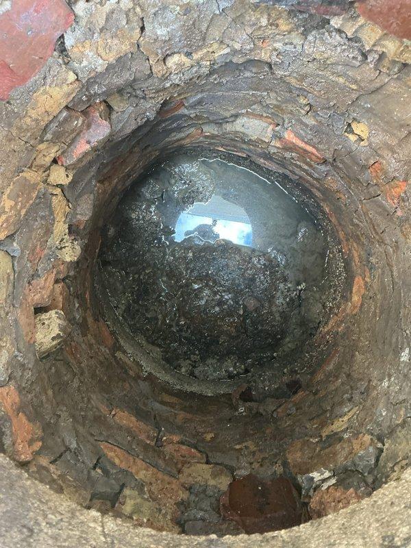 Performed camera inspection to diagnose recurring toilet clogs and slow drainage issues that developed following a basement flooding incident. Video inspection revealed underground drainage system accessing main sewer line through exterior cleanout pit, with brick-lined access shaft showing significant deterioration and debris accumulation at the base that may be contributing to drainage restrictions.