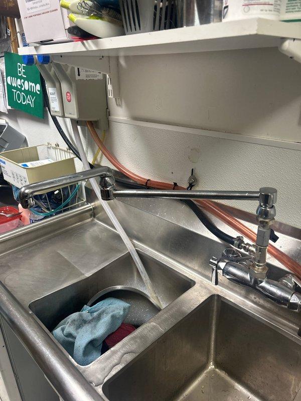 Completed installation of commercial-grade stainless steel sink system with multi-compartment basin configuration and pre-rinse spray valve assembly. Installed chrome-finished pull-down faucet with wall-mounted support bar, connected hot and cold water supply lines using copper piping, and mounted brass valve fittings for the pre-rinse unit. All fixtures were properly secured, tested for leaks, and confirmed operational for commercial kitchen use.