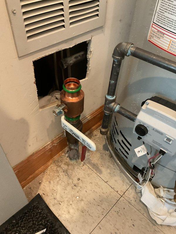 Successfully replaced the main house 1 1/2" ball valve by cutting out the existing valve assembly and freeing the copper line. Cut access opening in wall to properly unsweat the 1 1/2" brass 90-degree elbow fitting, allowing for complete removal and replacement of the valve. Installed new ball valve with compression fittings, tested system for proper operation and verified no leaks at all connection points.