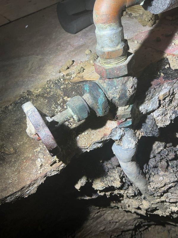 Conducted comprehensive assessment of residential drain and sewer system revealing extensive corrosion throughout basement plumbing infrastructure. Primary concerns identified include severely deteriorated valve assemblies with advanced rust and blue-green patina indicating copper corrosion, heavy mineral deposits and calcification on multiple pipe sections, and mixed-material connections between galvanized steel and copper components showing signs of galvanic corrosion. Exterior evaluation documented ground conditions near foundation with exposed soil transitions and concrete borders, suggesting potential drainage or sewer line access points requiring further investigation for proper repair planning and material replacement specifications.