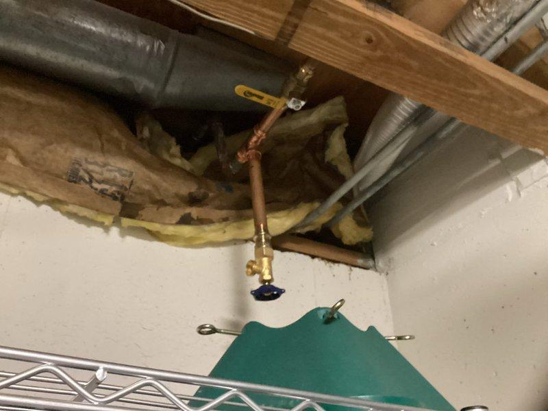 Responded to emergency repair call for burst copper pipe in basement utility area. Located the compromised section of copper piping along exposed ceiling joists near the wall junction. Shut off water supply using existing brass shutoff valve with red wheel handle to isolate the affected line. Removed damaged section of copper pipe and installed new copper piping with brass compression fittings, creating a proper T-junction configuration. Secured all horizontal runs with copper pipe straps to wooden joists per code requirements. Tested all connections for leaks, restored water supply, and verified system integrity. Documented existing plumbing configuration including HVAC ductwork and insulated lines in the overhead space for future reference.