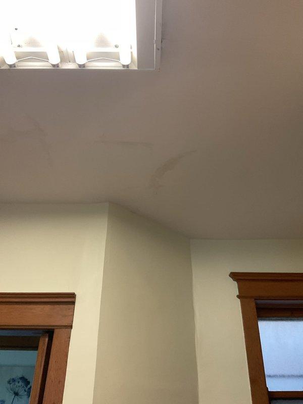 Responded to priority service call for water leak manifesting in ceiling of residential property. Conducted thorough investigation of affected area, including visual inspection of ceiling penetration points and architectural features in high-ceiling space. Accessed crawl space beneath flooring to locate source of water intrusion. Identified plumbing system components in subfloor area with drainage aggregate present. Documented conditions of wooden floor joists showing moisture staining and discoloration, concrete block foundation wall, and PVC plumbing infrastructure. Photographed evidence of leak location and surrounding structural elements for repair assessment.