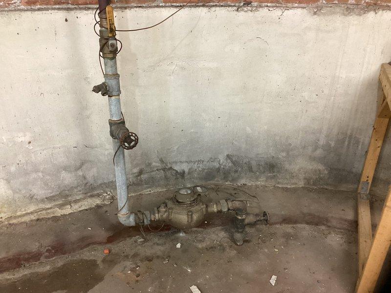 Completed comprehensive plumbing maintenance inspection of basement utility area, including evaluation of aging galvanized pipe assembly and shutoff valve system. Documented existing moisture damage, wall deterioration, and condition of mechanical equipment including water heating components and associated copper piping with shutoff valves for maintenance records and future service planning.
