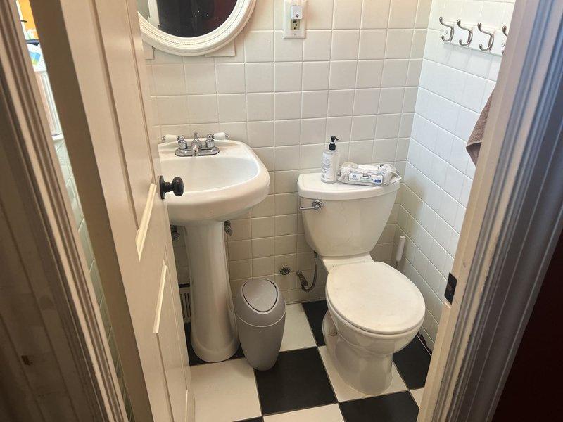 Conducted comprehensive assessment of residential plumbing system for complete home repipe estimate. Evaluated existing copper piping infrastructure throughout property, including main water supply lines, distribution piping, and fixture connections. Inspected basement mechanical room where main water service enters the building, documenting current copper pipe configuration, shutoff valves, and water heater connections with green O-ring gaskets at junction points. Assessed bathroom plumbing serving pedestal sink with chrome fixtures and toilet, examining supply lines and drain connections behind finished tile walls and checkered floor. Photographed existing piping conditions, valve placements, and access points to determine scope of work required for full residential repipe project. Identified routing requirements through basement joists and wall cavities to minimize disruption during future installation.