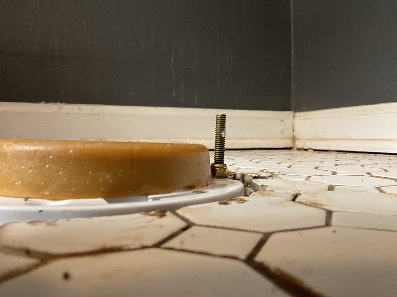 Responded to service call for toilet instability caused by broken closet bolt at base. Inspected second toilet and identified improper installation with excessive wax ring stacking (three rings) due to misalignment between fixture and waste pipe. Documented conditions of both fixtures with photographs showing compromised floor flange hardware and deteriorated hex tile flooring around toilet base. Provided estimate for proper reinstallation with flange repair and correct wax ring application.