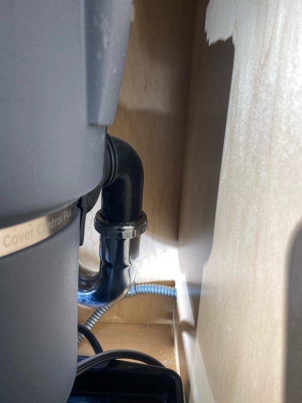 Responded to emergency call for kitchen sink leak originating from garbage disposal area. Upon inspection, identified active water leak at disposal unit connection point. Assessed mounting assembly, drain connections, and discharge plumbing for source of leak. Tightened mounting flange and discharge elbow connections, verified proper seal at sink drain interface. Inspected flexible supply lines and confirmed no damage to water supply plumbing. Tested disposal unit operation and checked all connections under running water to ensure leak was fully resolved.