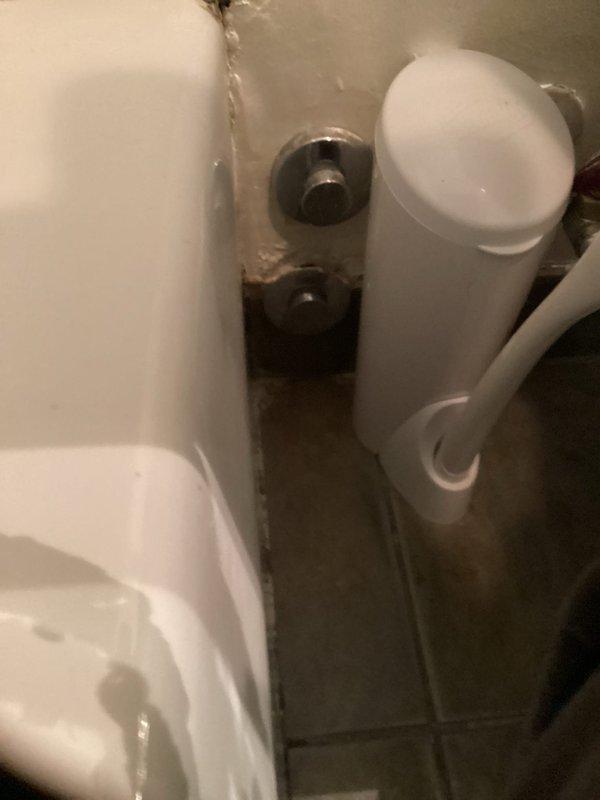 Completed installation of chrome-finished single-handle shower mixing valve with circular escutcheon plate and lever-style control handle on tiled wall surface. Building water supply was shut down at 9am to facilitate the fixture installation. Also installed wall-mounted plumbing connections near toilet fixture, with two metallic valve assemblies mounted on bathroom wall.