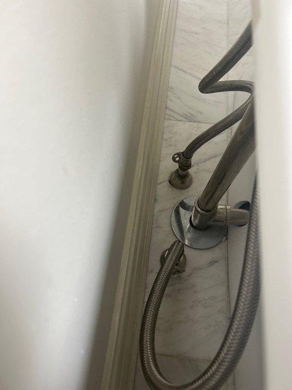Installed handheld shower attachment with chrome mounting bracket and flexible braided metal hose on white tiled shower wall. Serviced vintage-style deck-mounted bathtub faucet assembly with polished chrome fixtures, white porcelain handle accents, and handheld shower component on freestanding tub, ensuring all connections were secure and fixtures were operating properly.